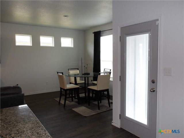 dining space with baseboards and dark wood-type flooring
