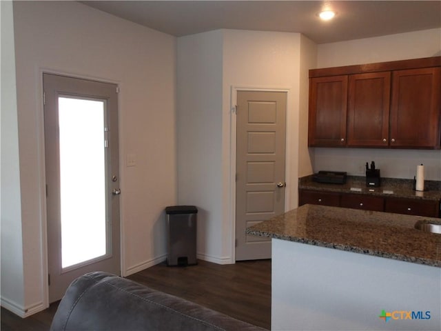 kitchen with dark stone counters, dark wood finished floors, baseboards, and plenty of natural light