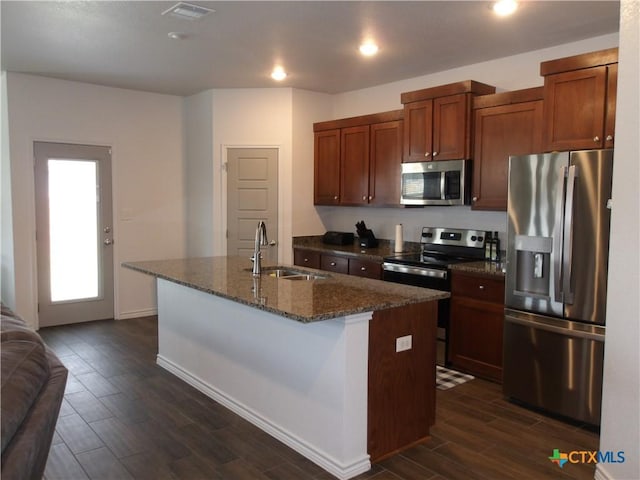 kitchen featuring dark wood finished floors, an island with sink, stainless steel appliances, visible vents, and a sink