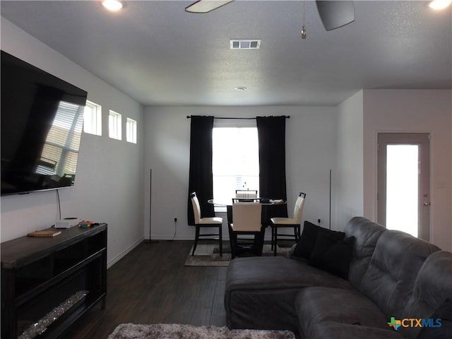 living room with baseboards, visible vents, and dark wood-style floors