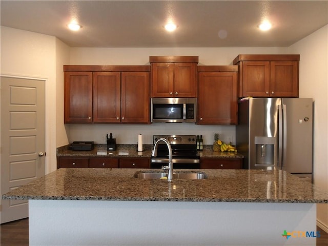 kitchen with dark stone countertops, stainless steel appliances, dark wood-style floors, and a sink