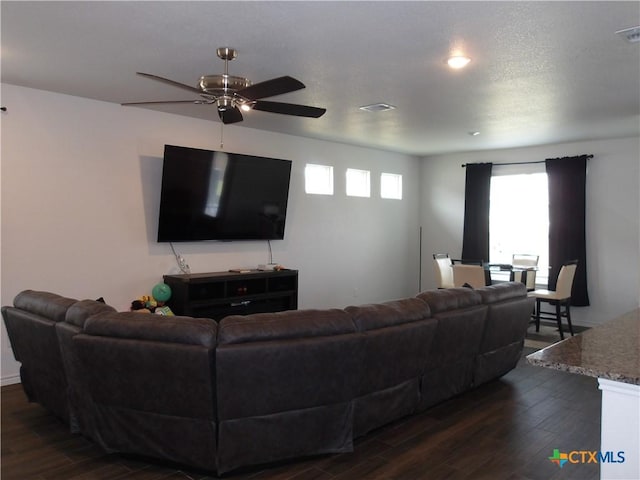 living area with dark wood finished floors, a ceiling fan, visible vents, and plenty of natural light