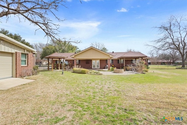 back of house featuring brick siding, a lawn, and a patio