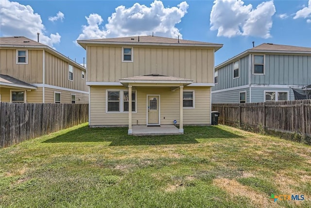 rear view of house featuring a lawn and a patio