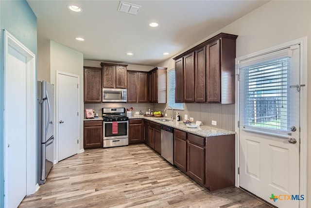 kitchen with light hardwood / wood-style floors, sink, a healthy amount of sunlight, appliances with stainless steel finishes, and light stone counters