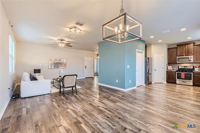 kitchen featuring hardwood / wood-style flooring, hanging light fixtures, appliances with stainless steel finishes, and ceiling fan with notable chandelier