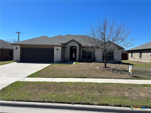 view of front of house with stone siding, driveway, an attached garage, and a front lawn