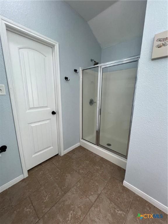 bathroom featuring a shower with shower door and vaulted ceiling