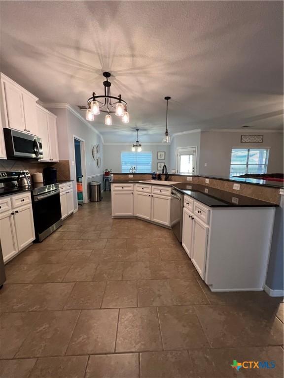 kitchen with pendant lighting, dishwasher, white cabinets, and sink