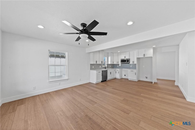 unfurnished living room with ceiling fan, sink, and light wood-type flooring