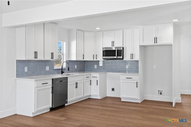 kitchen featuring sink, tasteful backsplash, stainless steel appliances, light hardwood / wood-style floors, and white cabinets