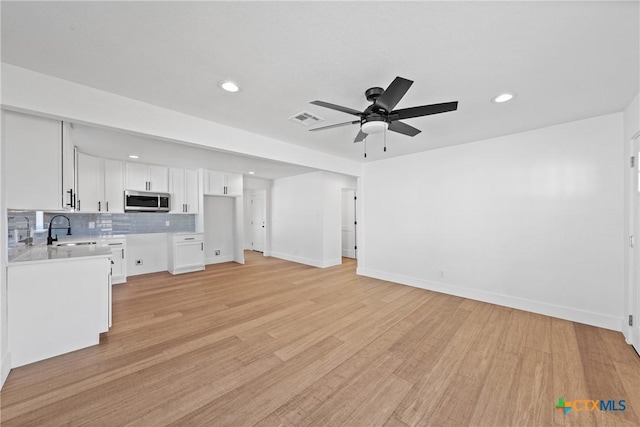 kitchen featuring sink, white cabinetry, light hardwood / wood-style flooring, ceiling fan, and backsplash