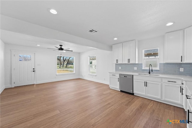 kitchen featuring sink, tasteful backsplash, light wood-type flooring, dishwasher, and white cabinets