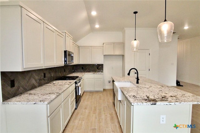 kitchen featuring pendant lighting, appliances with stainless steel finishes, light stone countertops, and white cabinets