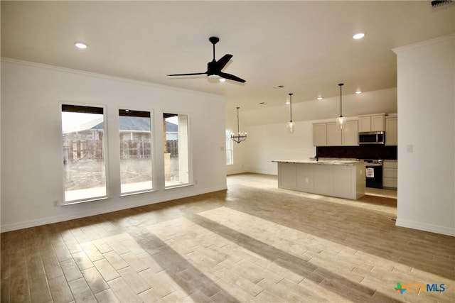 unfurnished living room with ornamental molding, ceiling fan with notable chandelier, and light wood-type flooring