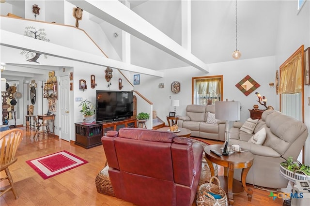 living room with stairway, high vaulted ceiling, and wood finished floors