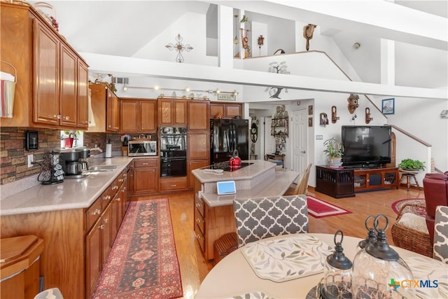 kitchen featuring visible vents, open floor plan, light countertops, black appliances, and brown cabinetry