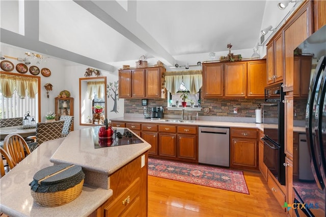 kitchen featuring a breakfast bar area, a kitchen island, brown cabinets, decorative backsplash, and black appliances