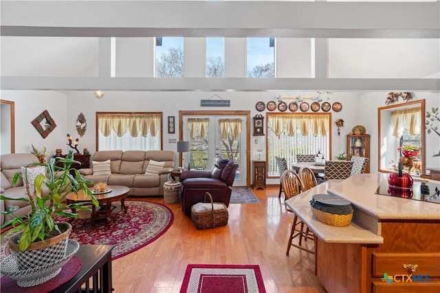 living area featuring french doors, a high ceiling, and light wood-style flooring