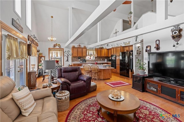 living room with vaulted ceiling, light wood-style flooring, and an inviting chandelier