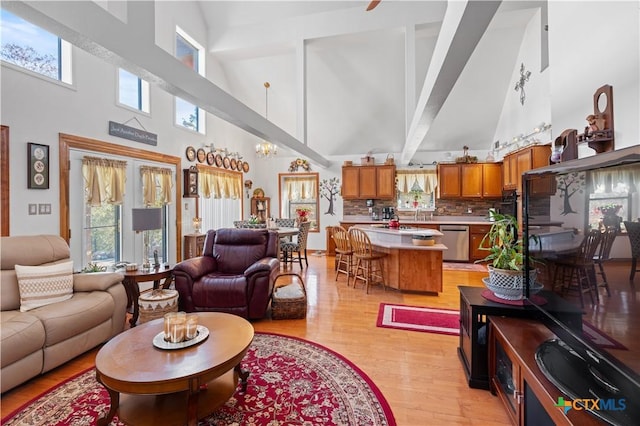 living area with a notable chandelier, a towering ceiling, and light wood finished floors