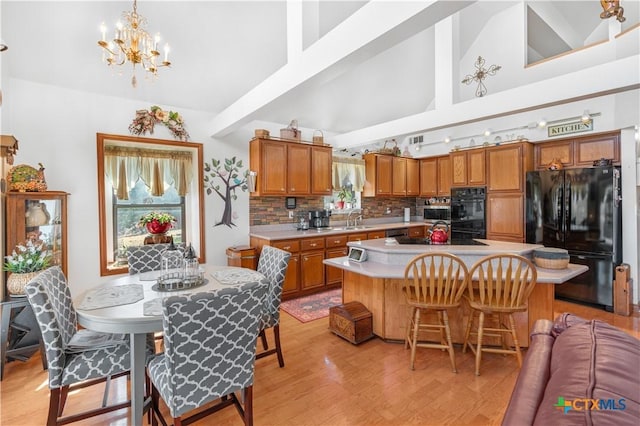 kitchen featuring decorative light fixtures, light countertops, brown cabinetry, a kitchen island, and black appliances