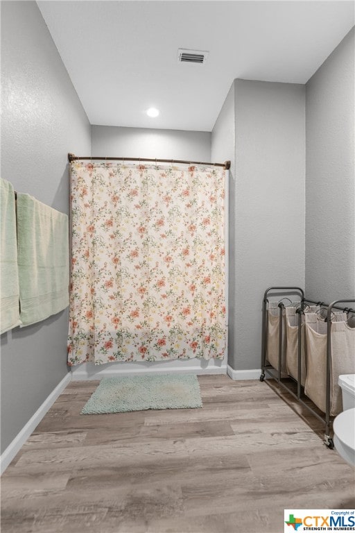 bathroom with hardwood / wood-style flooring and toilet