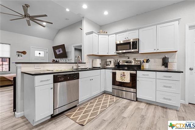 kitchen featuring white cabinets, vaulted ceiling, kitchen peninsula, and appliances with stainless steel finishes