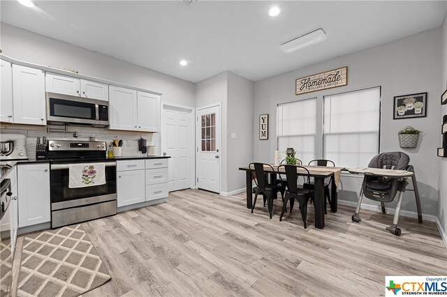 kitchen featuring white cabinetry, appliances with stainless steel finishes, backsplash, and light hardwood / wood-style floors