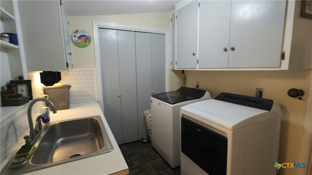 clothes washing area featuring washer and clothes dryer, sink, cabinets, and ornamental molding