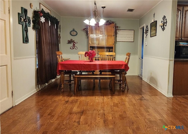 dining space with hardwood / wood-style floors, crown molding, and an inviting chandelier