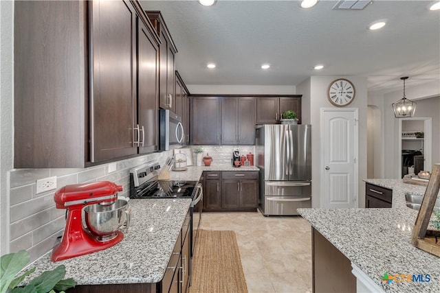 kitchen with visible vents, tasteful backsplash, stainless steel appliances, light stone countertops, and dark brown cabinets