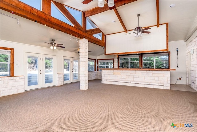 unfurnished living room with a healthy amount of sunlight, french doors, ceiling fan, and carpet flooring