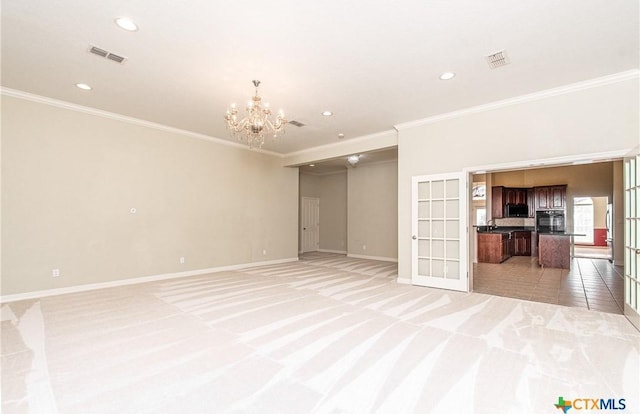 unfurnished living room featuring ornamental molding, light colored carpet, a chandelier, and french doors