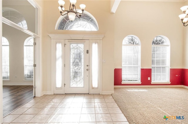 tiled foyer entrance featuring a notable chandelier, a towering ceiling, and plenty of natural light