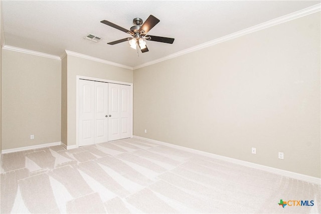 unfurnished bedroom with crown molding, a closet, ceiling fan, and light carpet