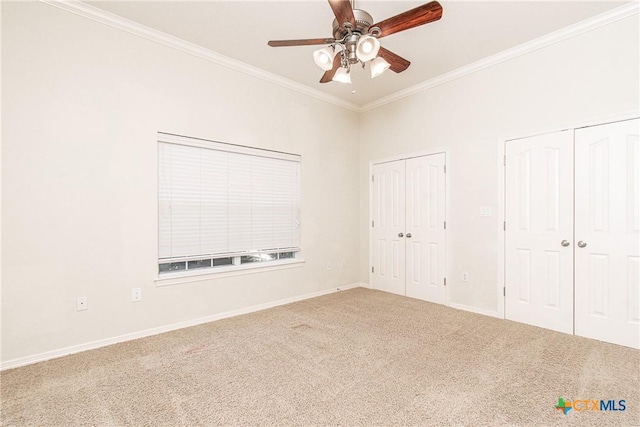 unfurnished bedroom with crown molding, carpet flooring, two closets, and ceiling fan