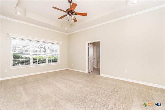 empty room featuring ornamental molding, light colored carpet, ceiling fan, and a tray ceiling