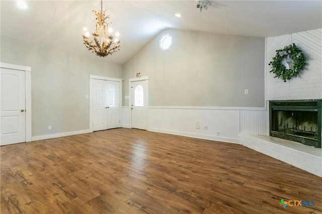 508 N Wall St, Belton, TX 76513 - unfurnished living room with wood finished floors, high vaulted ceiling, a brick fireplace, and a chandelier