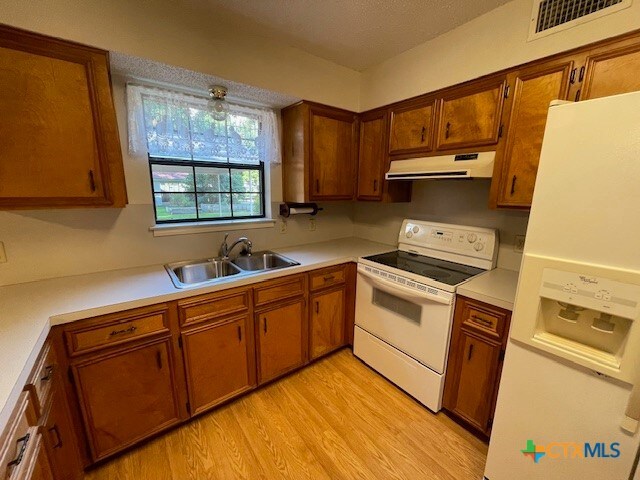 kitchen with white appliances, sink, and light hardwood / wood-style floors