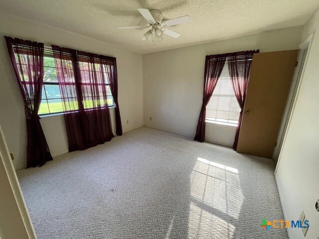 carpeted empty room featuring a textured ceiling and ceiling fan