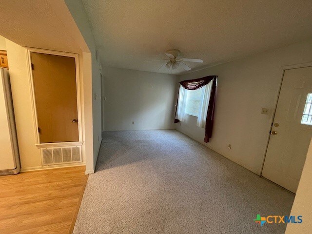 interior space with ceiling fan, a textured ceiling, and light hardwood / wood-style flooring