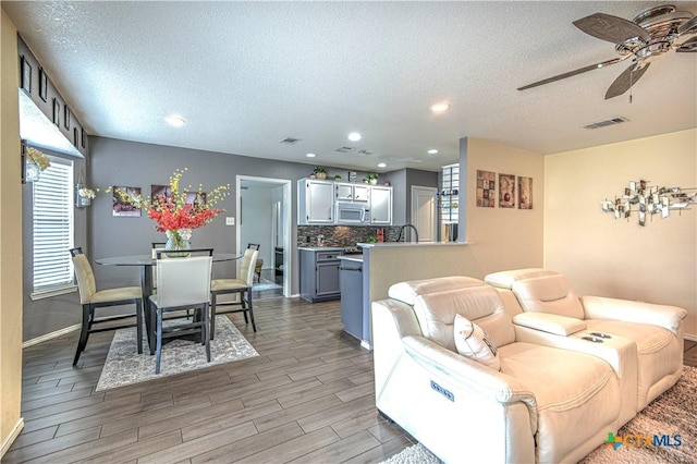 living room featuring visible vents, ceiling fan, a textured ceiling, wood finish floors, and recessed lighting