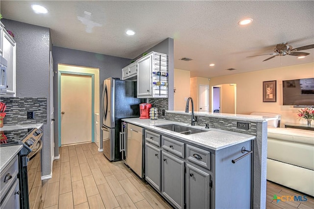 kitchen with stainless steel appliances, visible vents, open floor plan, a sink, and a peninsula