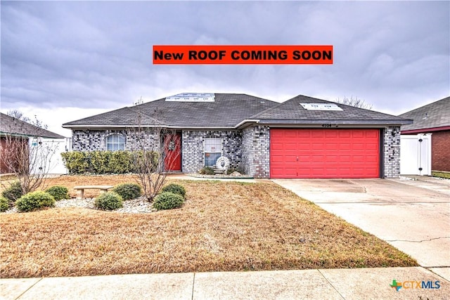 view of front of home featuring concrete driveway, an attached garage, and brick siding