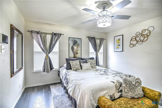 bedroom with a textured ceiling, baseboards, wood finished floors, and a textured wall