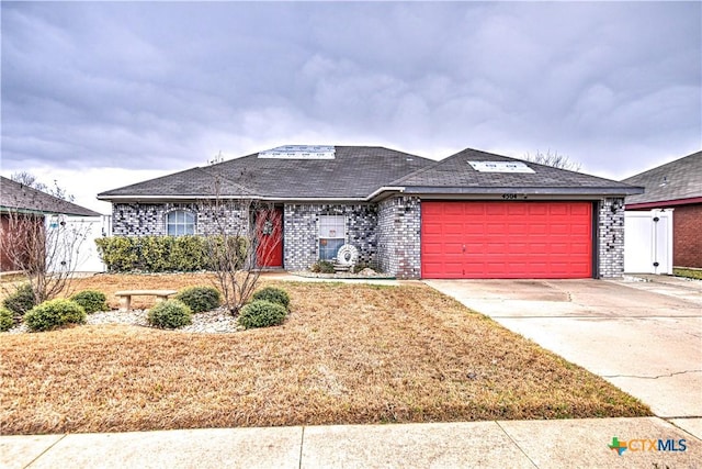 ranch-style house with driveway, brick siding, and an attached garage