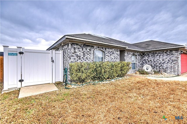 view of front of property with a garage, brick siding, a front lawn, and a gate