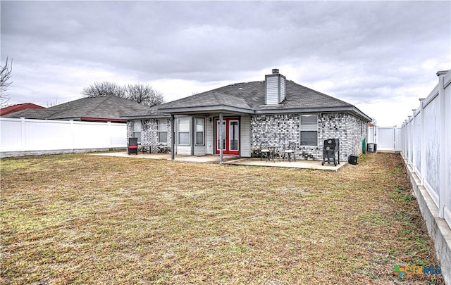 rear view of house featuring a chimney, a lawn, central AC, a patio area, and a fenced backyard