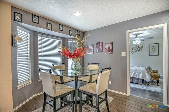 dining area with a textured wall, ceiling fan, a textured ceiling, wood finished floors, and baseboards